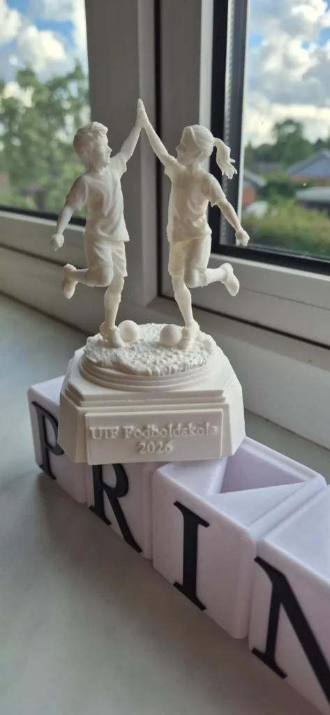 Fodboldtrofæ pige og dreng hopper og giver hinanden highfive